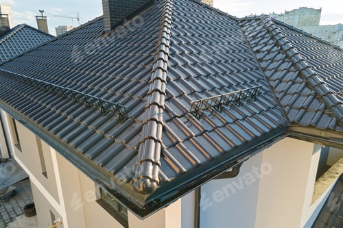 Preview: Closeup snow guard for safety in winter on house roof top covered with ceramic shingles.
