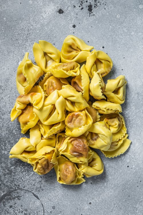 Preview: Uncooked raw ravioli with Mozzarella and Tomato. Gray background. Top view