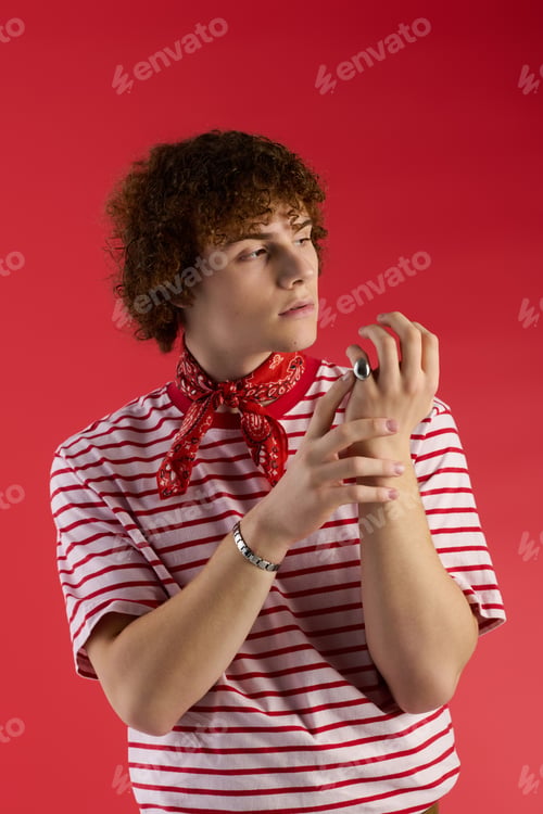 Preview: Teen boy showcases vibrant style against a bold red backdrop with confidence and flair