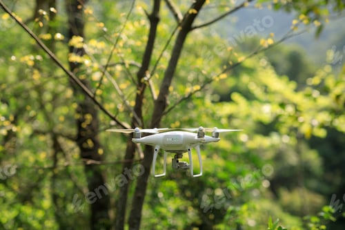 Preview: White drone with camera flying in spring tropical forest