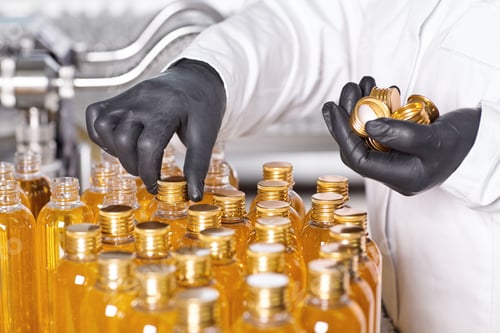 Preview: Laboratory worker wearing white medical gown and black rubber gloves holding robs in one hand and tw