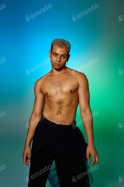 Preview: Young shirtless man with dyed hair poses confidently in artistic studio setting
