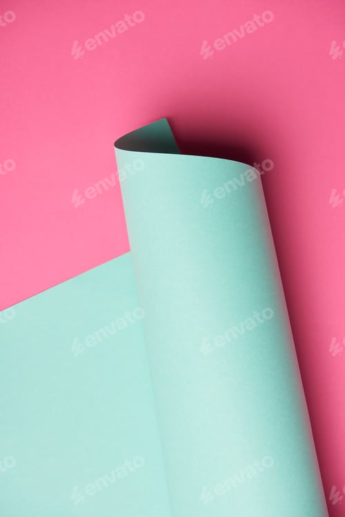 Preview: close-up view of rolled turquoise paper on pink background