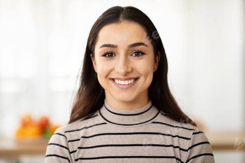 Preview: Headshot of cheerful young pretty arab lady looking at camera in light living room interior