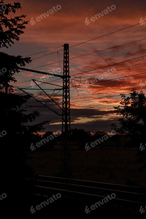 Preview: Vertical silhouette shot of powerlines on the side of a street during sunset
