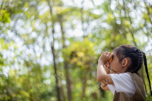 Preview: Happy Little Asian girls looking ahead and smiling child with the binoculars in the park.