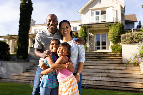 Preview: Outdoors, diverse family of four smiling and embracing in front of their home