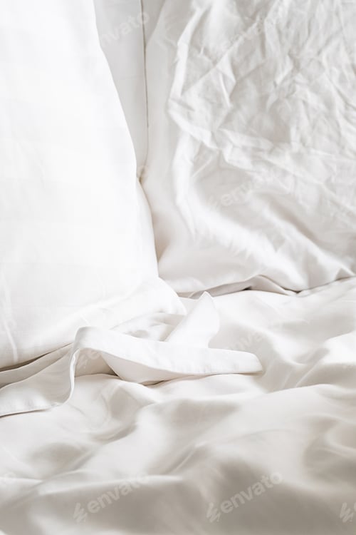 Preview: Soft white pillows on bedding, close up.