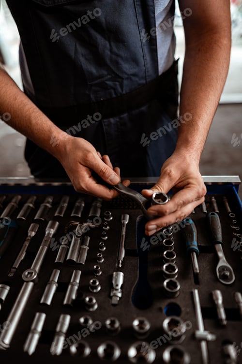 Preview: Worker inspects tools while preparing for a job in a workshop environment in the afternoon