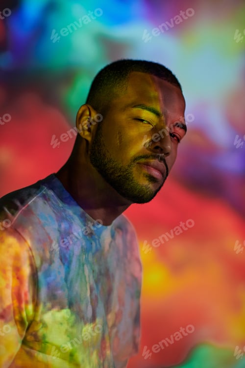 Vista previa: portrait of handsome man looking at camera in colourful digital projector lights, fashion concept