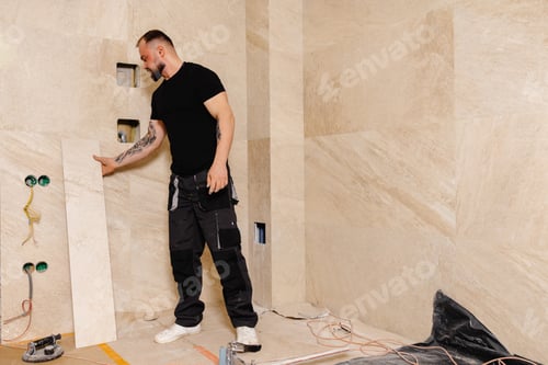Preview: Construction Worker Installing Large Travertine Tiles in Modern Bathroom