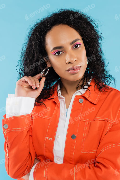 Preview: portrait of trendy african american woman touching hoop earring and looking at camera isolated on