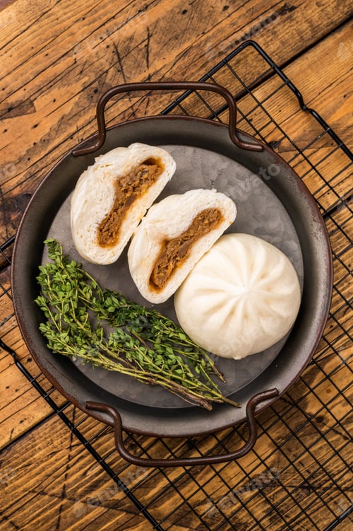 Preview: Chinese Bao Baozi steam bun with meat on steel tray. wooden background. top view