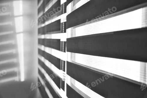 Preview: Sun shining through window blinds throwing shadows on the wall in black and white