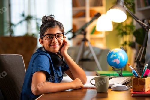Preview: Asian Indian school girl studying at home on computer