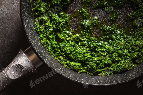 Preview: Fried chopped spinach leaves on a frying pan close-up