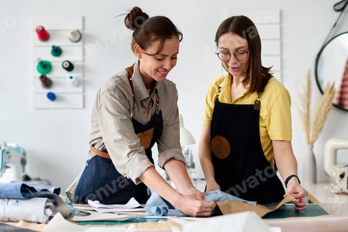 Preview: Two female tanners choosing piece of leather for sewing new apparel