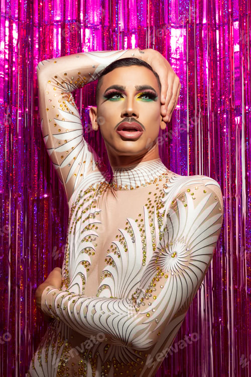 Preview: young drag queen with short hair and mustache posing with fuchsia color background
