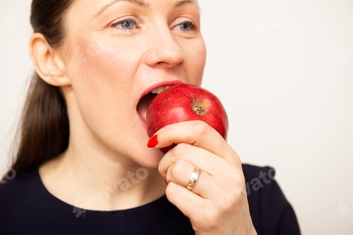 Preview: Close-up of beautiful young woman face eating an apple . White isolated background