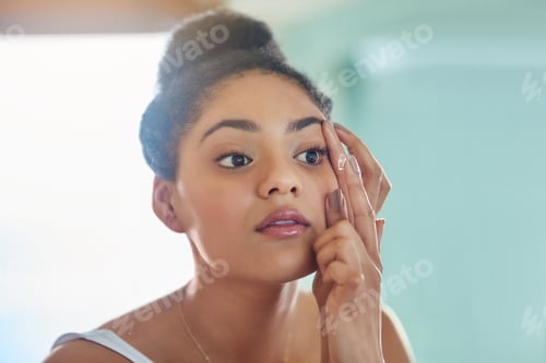 Preview: Shot of an attractive young woman putting in her contact lenses at home