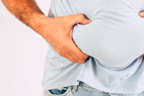 Preview: Close up of caucasian man's hand holding belly abdominal fat - concept of junk food and diet