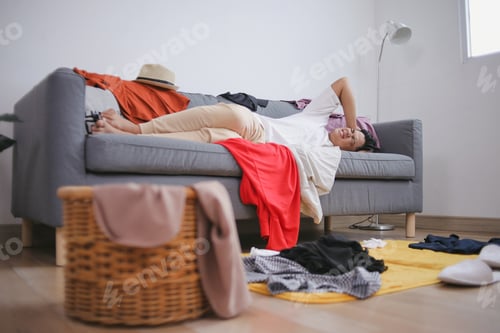Preview: Stressed Young Man Lying On Sofa Suffering Headache With Few Clothes Messed Up The Room