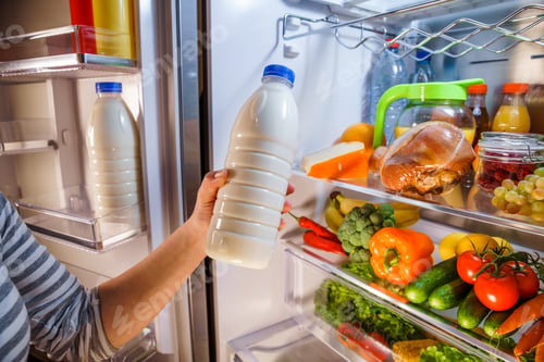 Preview: Woman takes the milk from the open refrigerator