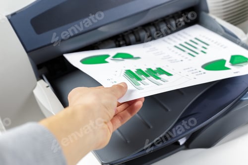 Preview: Person removes printed charts from a printer in an office space during daylight hours
