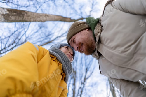 Preview: Father and child having a great time in a snowy forest on a winter day.