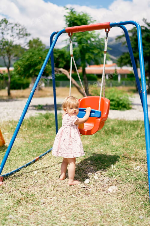 Preview: Little girl stands near a swing in the park