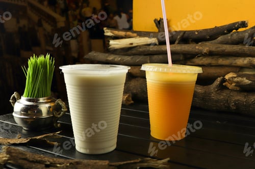 Preview: Closeup of delicious banana and orange shakes in plastic cups on the table