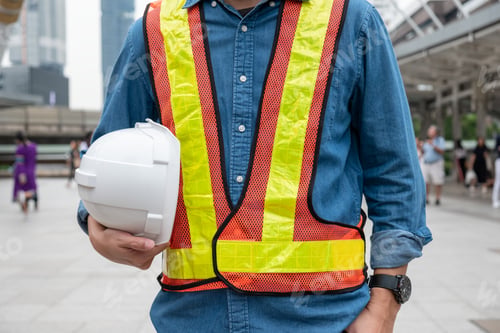 Preview: Constructor man in work vest holding safety helmet at workplace