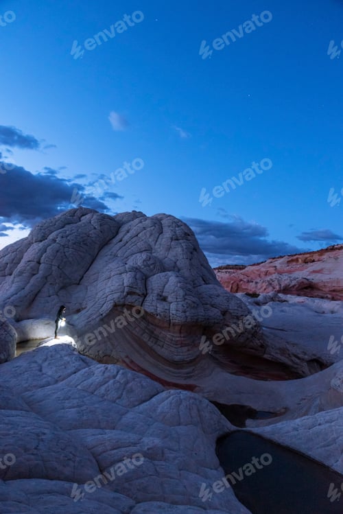 Preview: Explorer illuminating the way in a rugged terrain at twilight