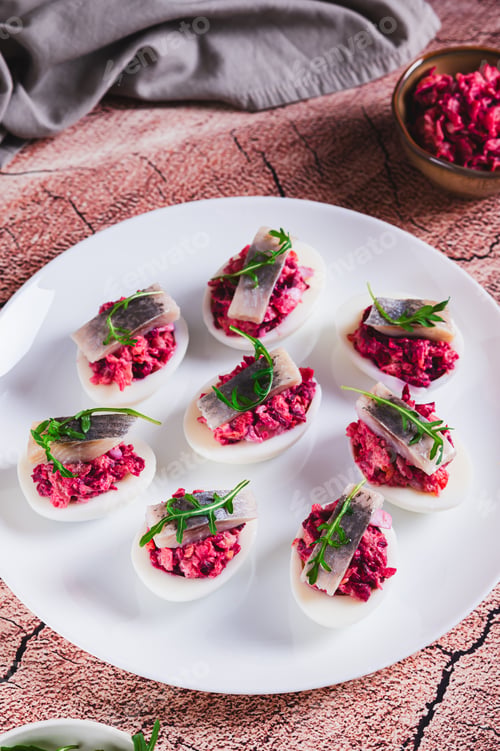 Preview: Eggs delived with vegetable salad, a piece of herring and arugula on a plate on the table vertical