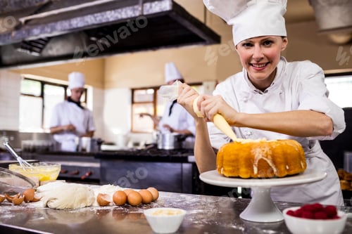 Preview: Female chef piping a cake in kitchen