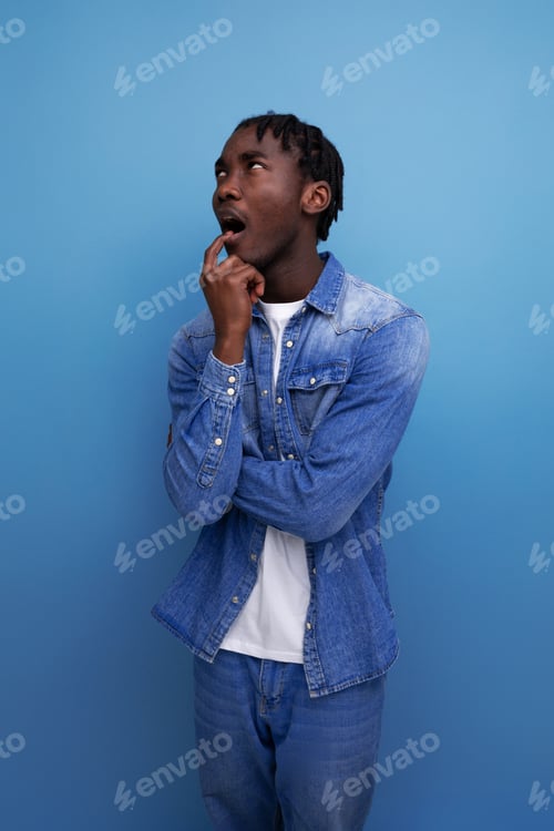 Preview: close-up portrait of a surprised young african guy with dreadlocks in a denim jacket