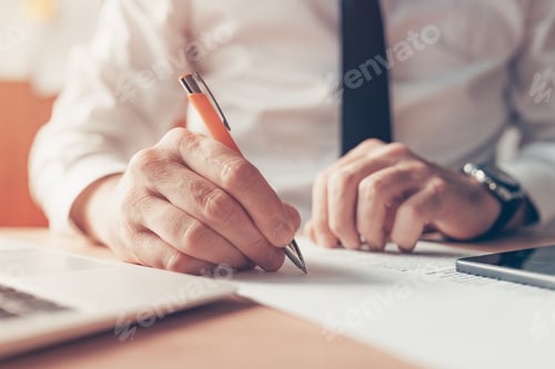 Preview: Businessman writing notes at office desk