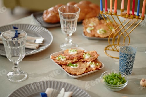 Preview: Hanukkah Table Displaying Potato Pancakes and Menorah with Lit Candles
