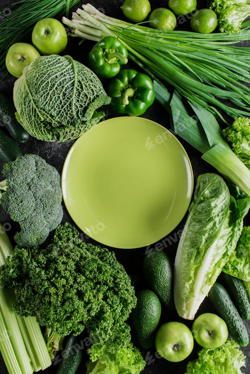 Preview: top view of green plate between green vegetables, healthy eating concept