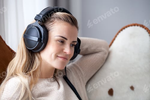 Preview: Young woman wearing headphones listening to music and relaxing at home