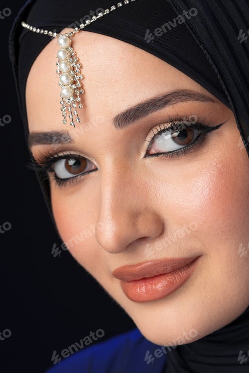 Preview: Woman wearing hijab with jewelry on forehead and subtle makeup in close-up view