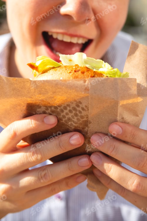 Preview: Woman eats burger with pleasure.