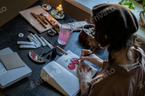 Preview: Imaginative illustrator drawing colorful animation painting with brush in sketch book in studio