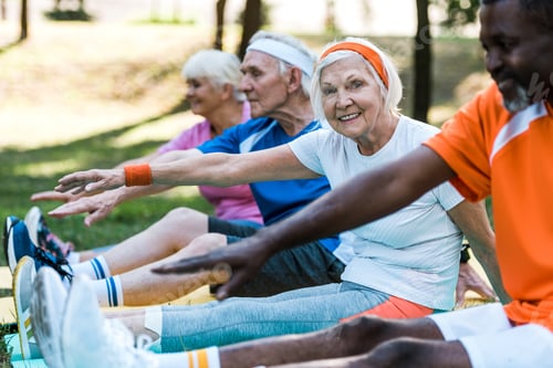 Preview: selective focus of multicultural retired women and men in sportswear exercising on fitness mats
