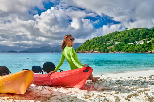 Preview: Woman Sitting On Kayak. Beautiful Petite Anse Beach With Palm Tree At Seychelles, Mahe