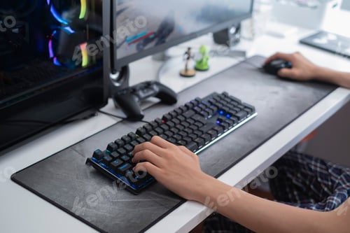 Preview: selective focus of a teenager hands playing on a gaming computer, with on a large gray mouse pad