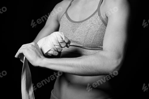 Preview: Girl tying a boxing bandage around her hand in the dark