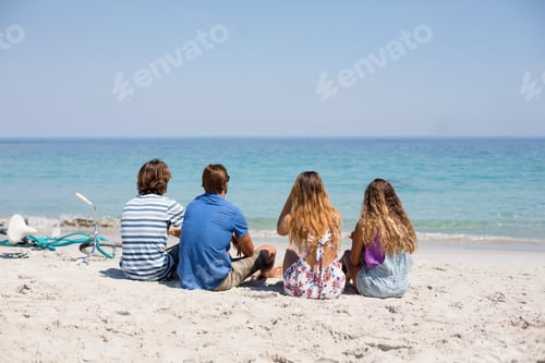Preview: Rear view of friends sitting on during sunny day