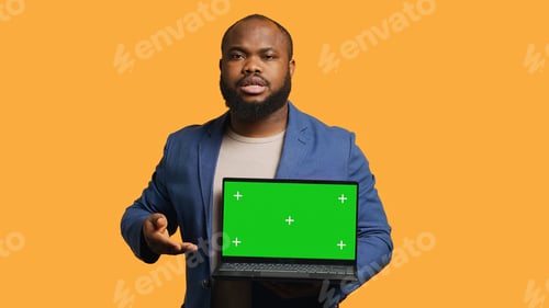 Preview: Cheerful person pointing towards chroma key notebook, studio background