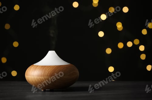 Preview: Modern essential oil diffuser on wooden table against blurred lights, space for text